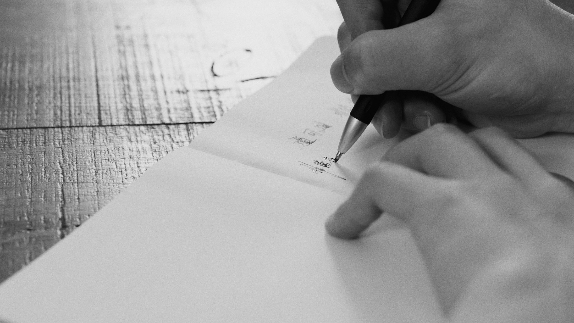A hand writing working notes on paper